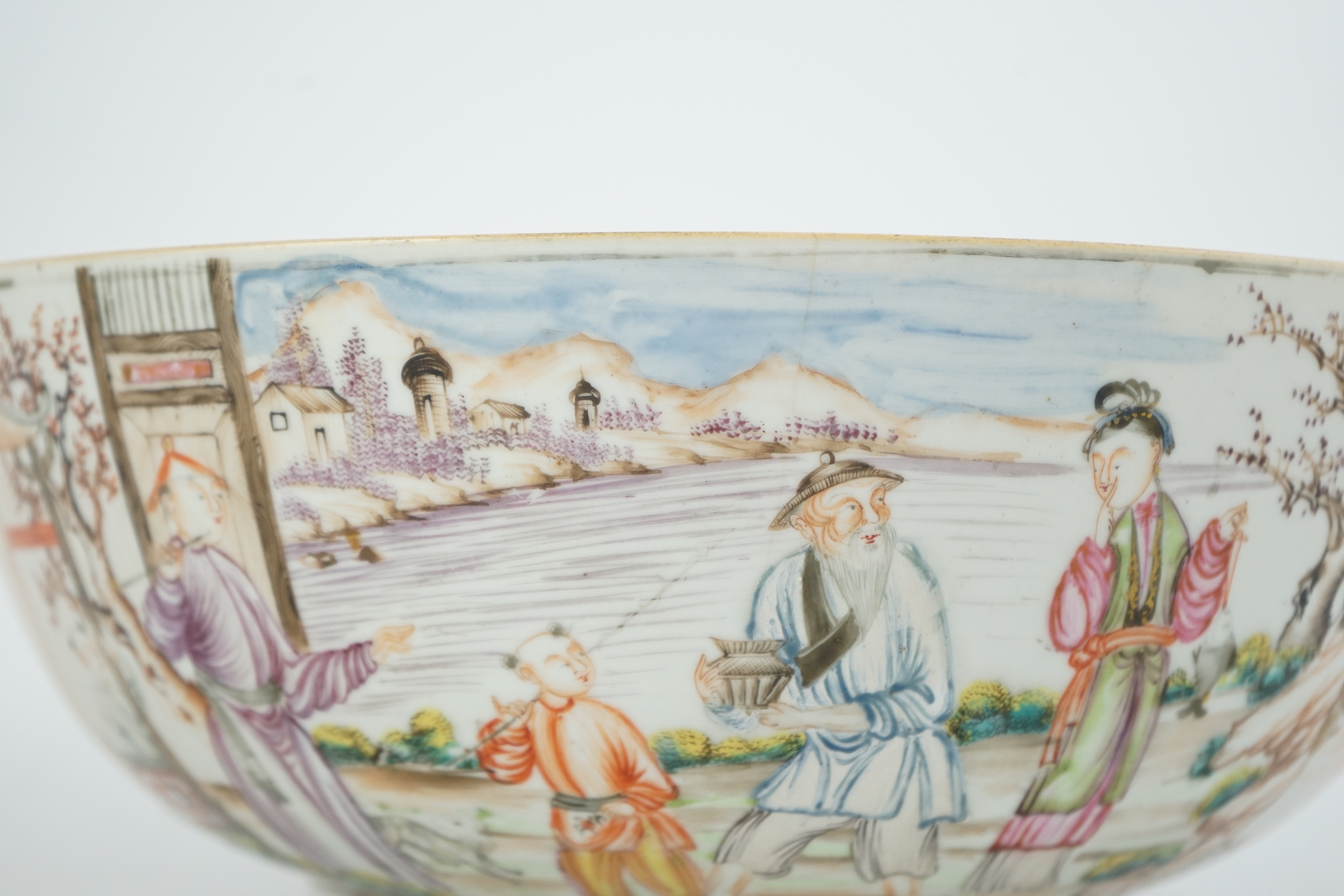 A Chinese famille rose ‘mandarin’ bowl, Qianlong period, painted with figures in a lakeside garden, between red enamelled landscape vignettes and cellular panels, 28.4cm diameter. Condition - there is a hairline crack to